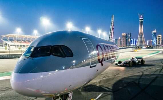Самолет Qatar Airways на фоне ночного автодрома Лусаил и небоскребов Дохи, акция на билеты Формулы-1 при транзите